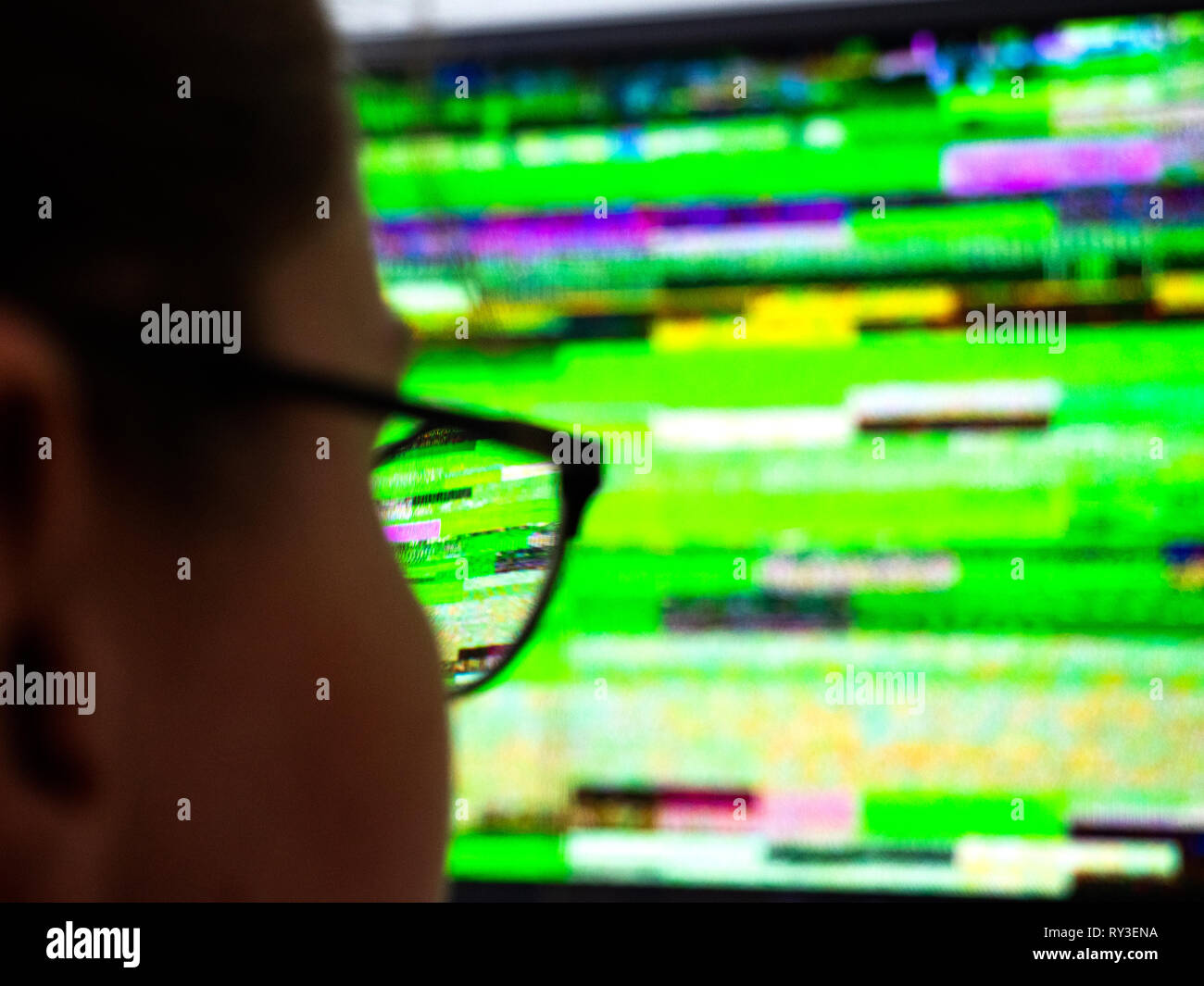 Détail vue arrière de l'optique lunettes femme portant à la recherche au mauvais signal bruit statique de son écran de télévision TVN numérique Banque D'Images
