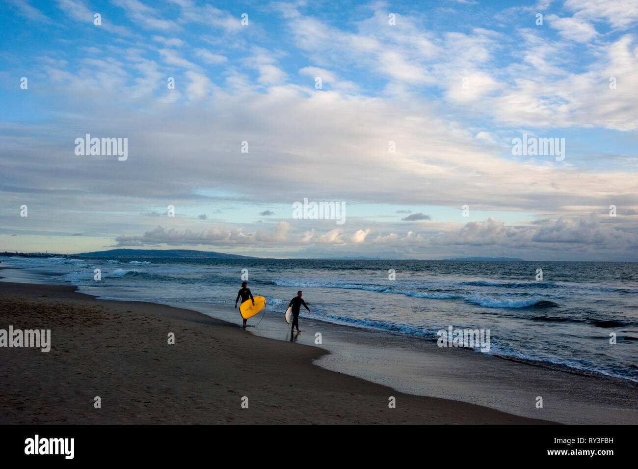 Les surfeurs sur la plage de Santa Monica avec Palos Verdes Peninsula en arrière-plan à Los Angeles, CA. Banque D'Images
