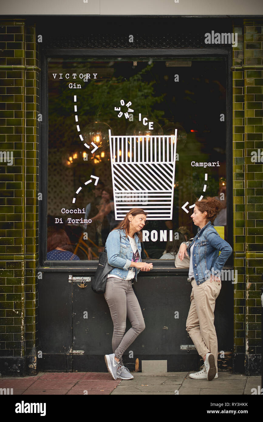 Londres, UK - août 2018. Deux jeunes filles boire une bière à l'extérieur d'un pub à Columbia Road, près de Shoreditch. Banque D'Images