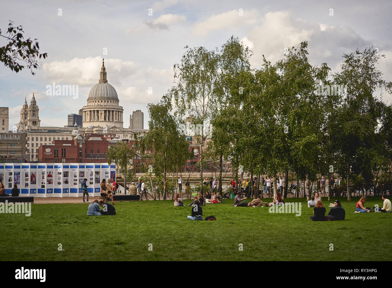 Londres, Royaume-Uni - Octobre 2018. Les gens assis dans le parc en face de la Tate Modern Museum, avec la Tamise et la Cathédrale St Paul. Banque D'Images