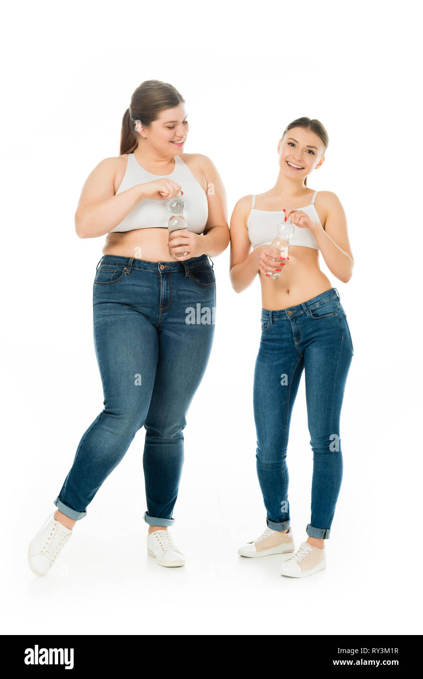 Heureux les femmes en surpoids et slim en jeans bouteilles avec de l'eau holding isolated on white Banque D'Images