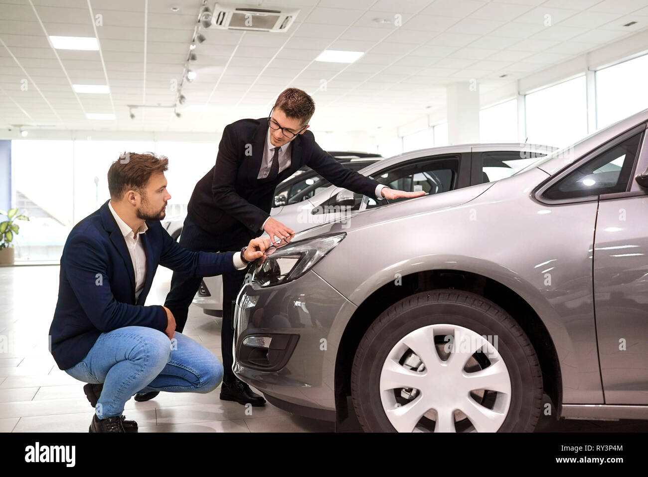Vendeur et client choisir une voiture dans le showroom Banque D'Images