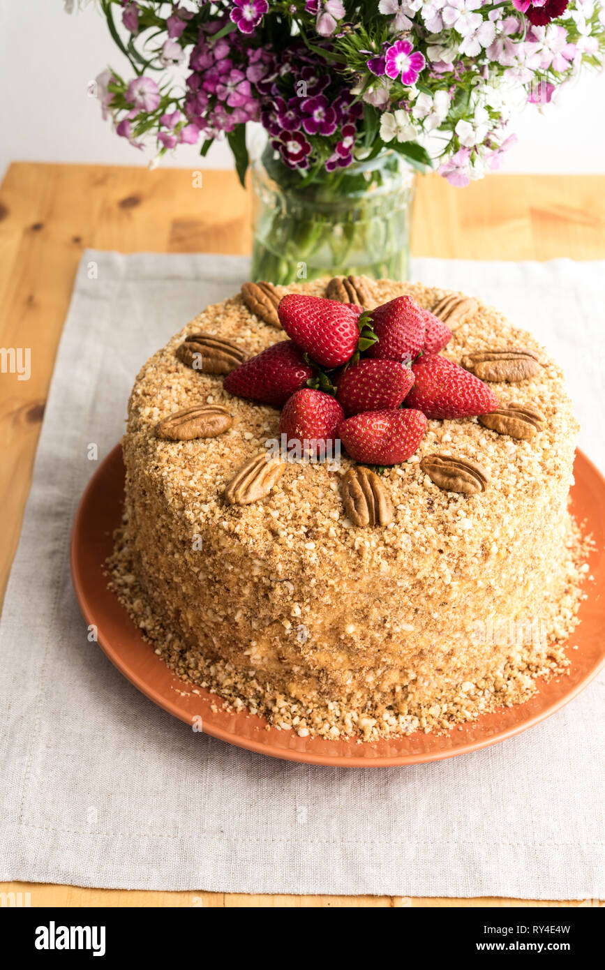 Gâteau de miel - Russe Medovik - recette traditionnelle russe. Partie gâteau coupe sur table avec plateau de fraises et de fleurs brunch Banque D'Images