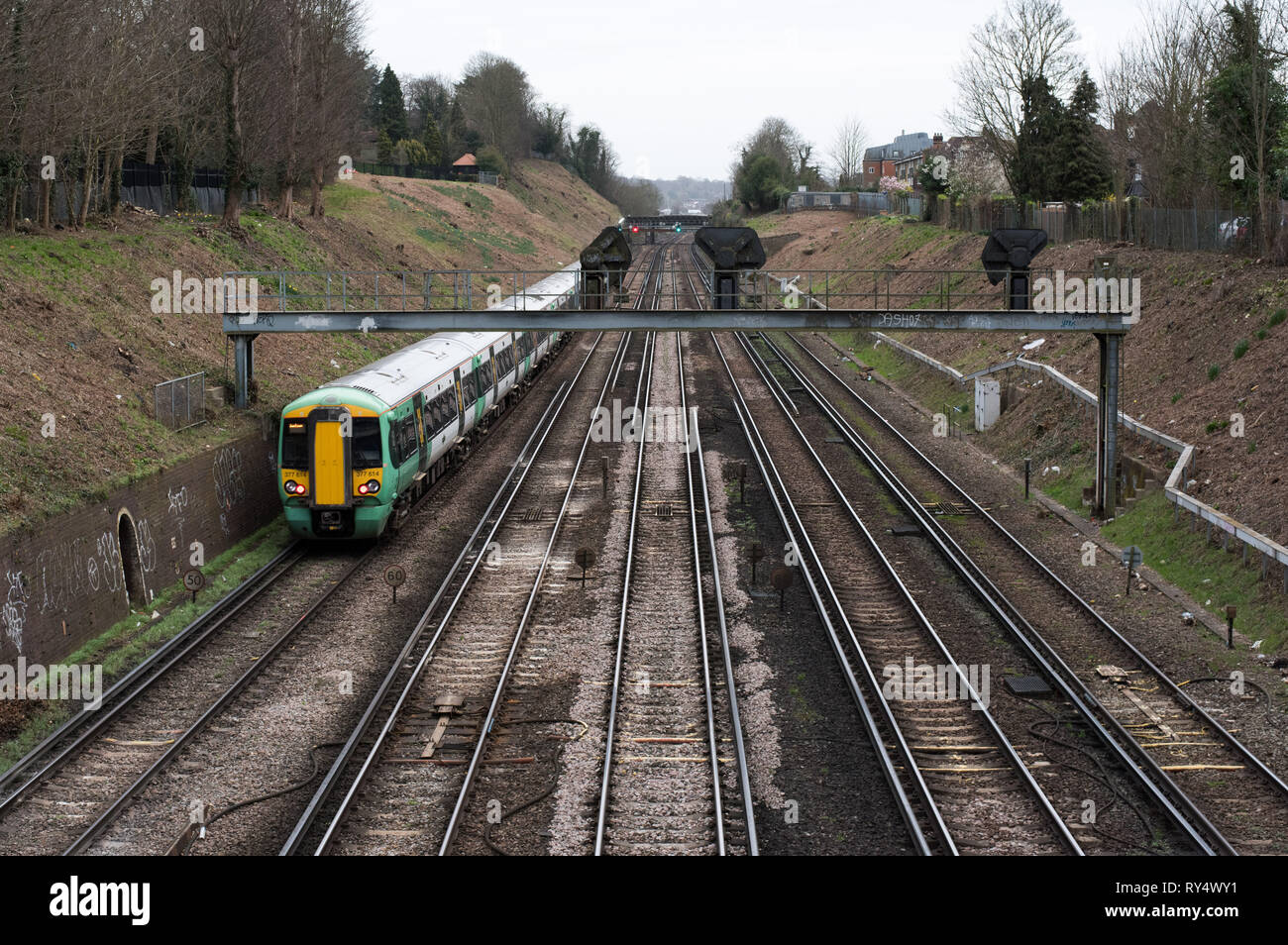Croydon, Grand Londres, UK - Mars 2019 : la voie de chemin de fer avec signal rouge et verte à l'arrière-plan et une couleur verte Southern Rail passant par Banque D'Images