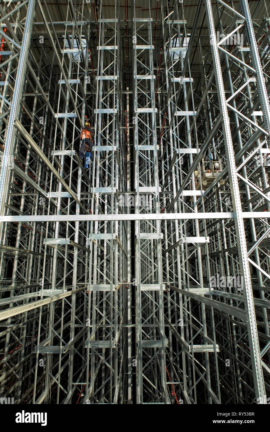 Dans Hochregallandschaft arbeitet mit ein Bauarbeiter und baut die Hochregale auf. Banque D'Images