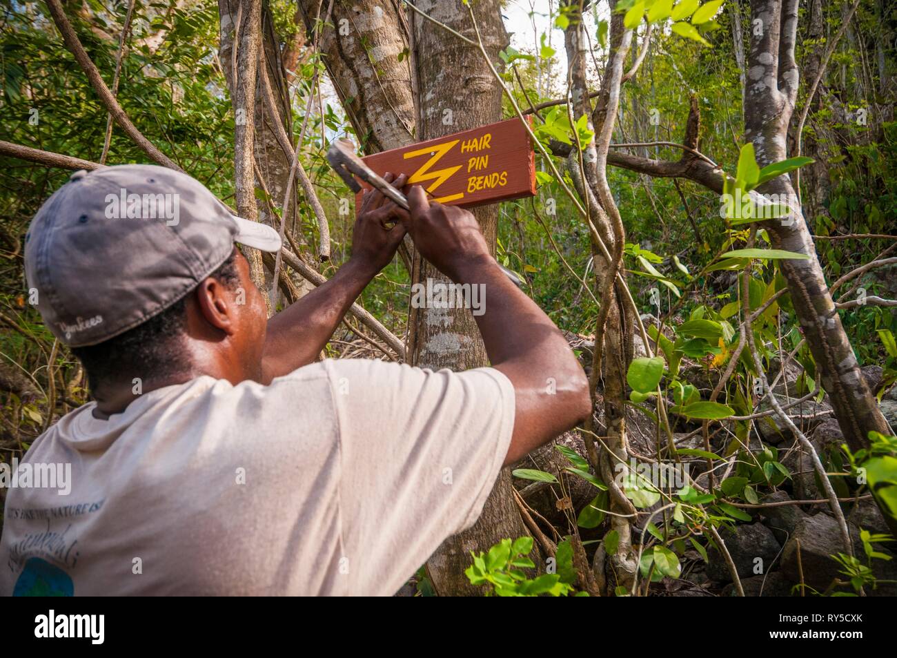 La Dominique, un guide présente un signe indiquant une forte montée en épingle à cheveux se penche sur l'article 1 de la Sentier de randonnée Waitukubuli qui traverse l'île Banque D'Images