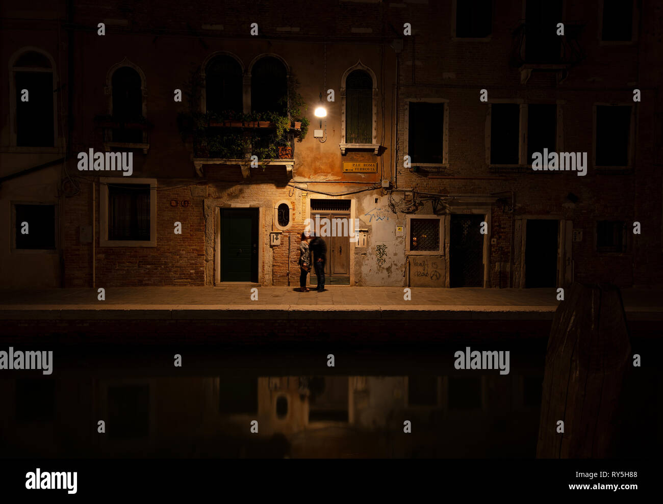 Un couple s'embrasser sous une lumière dans la ville romantique de Venise, Italie Banque D'Images