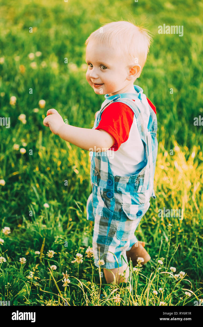 Heureux Petit Garçon enfant fonctionnant sur l'herbe verte prairie d'été Banque D'Images