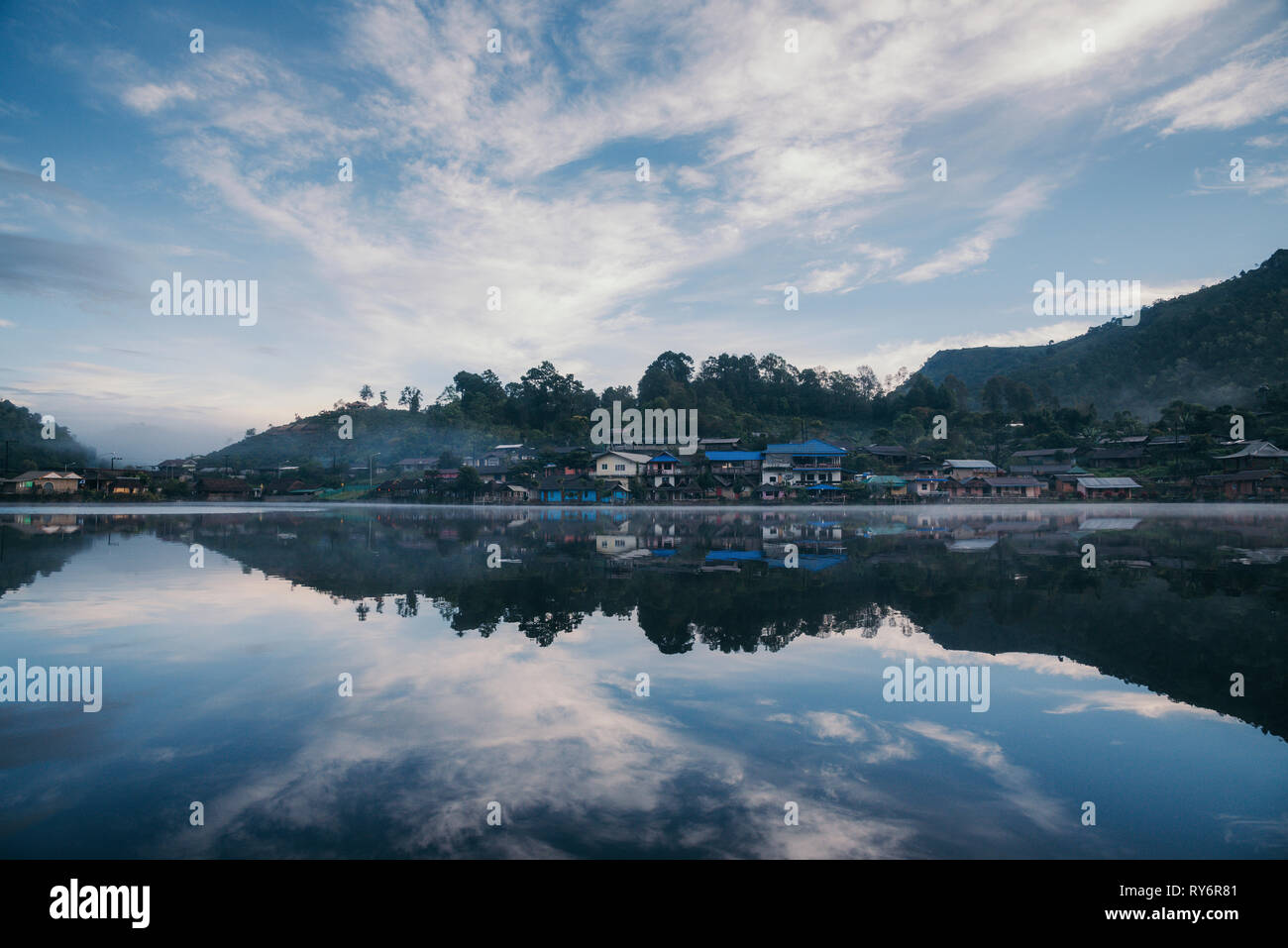 Réflexion sur le lac calme maisons against sky Banque D'Images