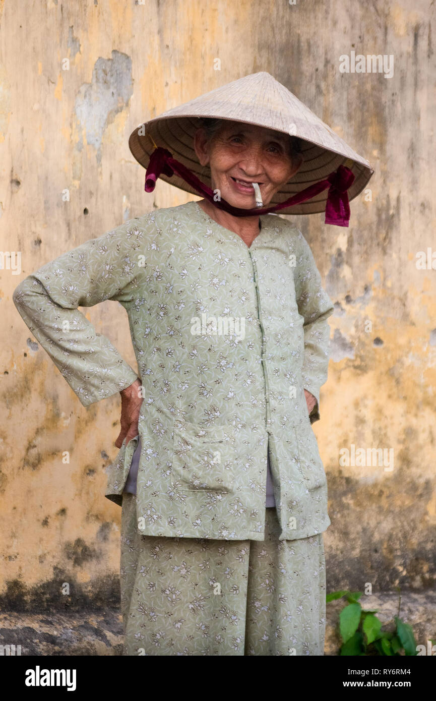 Smiling Old Vietnamienne Cigarette avec les mains sur les hanches - Hoi An, Vietnam Banque D'Images