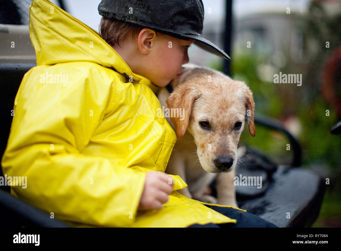 Jeune garçon embrassant son chien sous la pluie. Banque D'Images