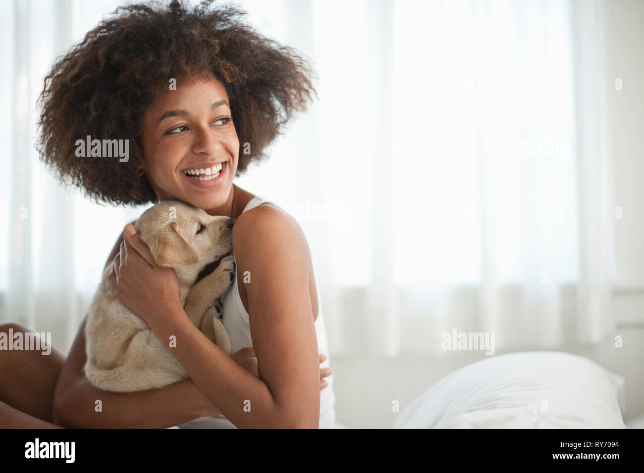Smiling young woman holding her Labrador chiot. Banque D'Images