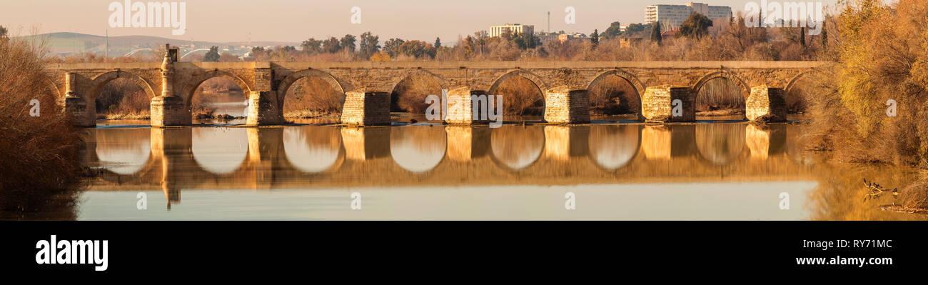 L'extérieur de la pierre longue traversée de pont romain Guadalquivir avec de l'eau paisible du soleil d'automne, à Cordoba, Espagne Banque D'Images