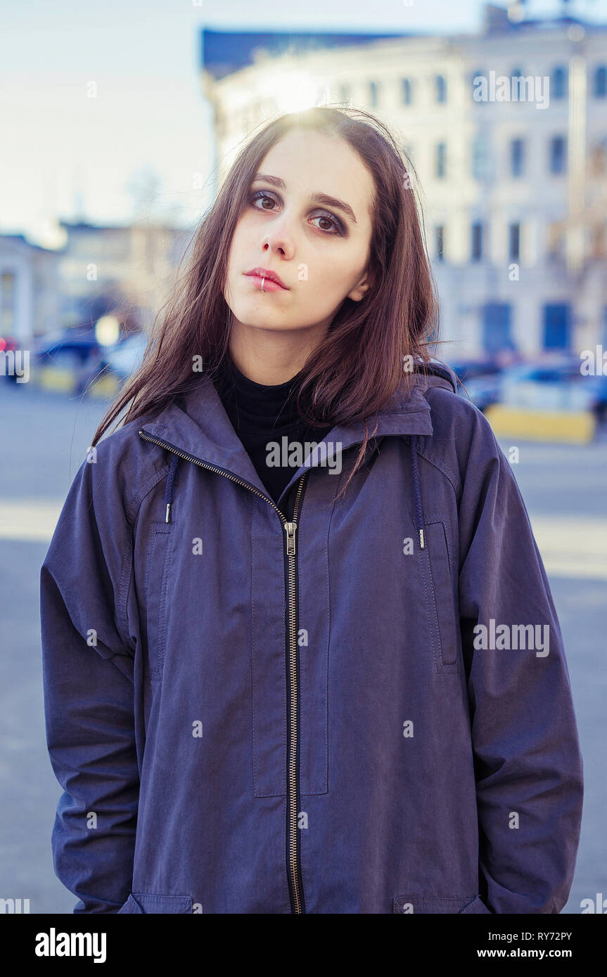 Portrait de femme hippie graves avec de longs cheveux debout contre les bâtiments on city street Banque D'Images