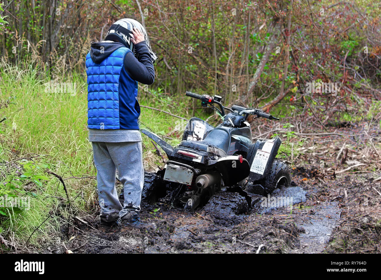 Un des jeunes garçons tient son casque coincé regardant son quad. Banque D'Images