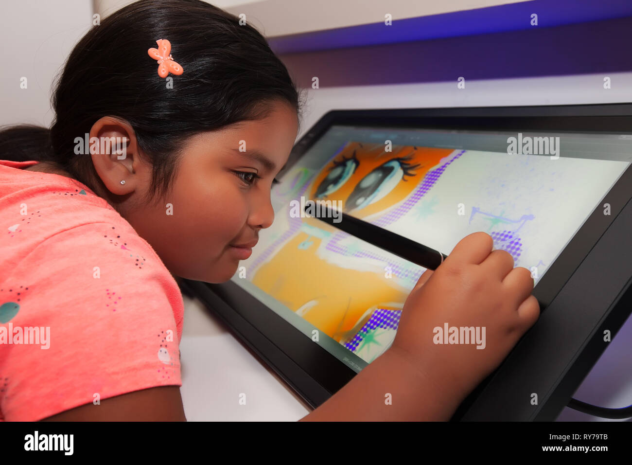 Jeune fille à l'aide d'un stylo numérique et tablette de dessin d'être créatif et de faire de l'art numérique dans une salle de classe. Banque D'Images