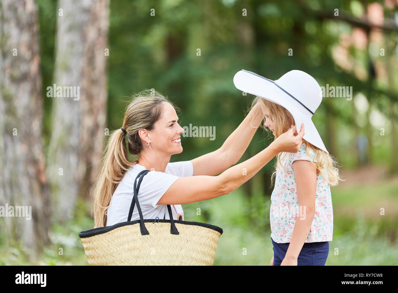 Mère met sur sa fille une dame élégante's hat sur vacances en été Banque D'Images