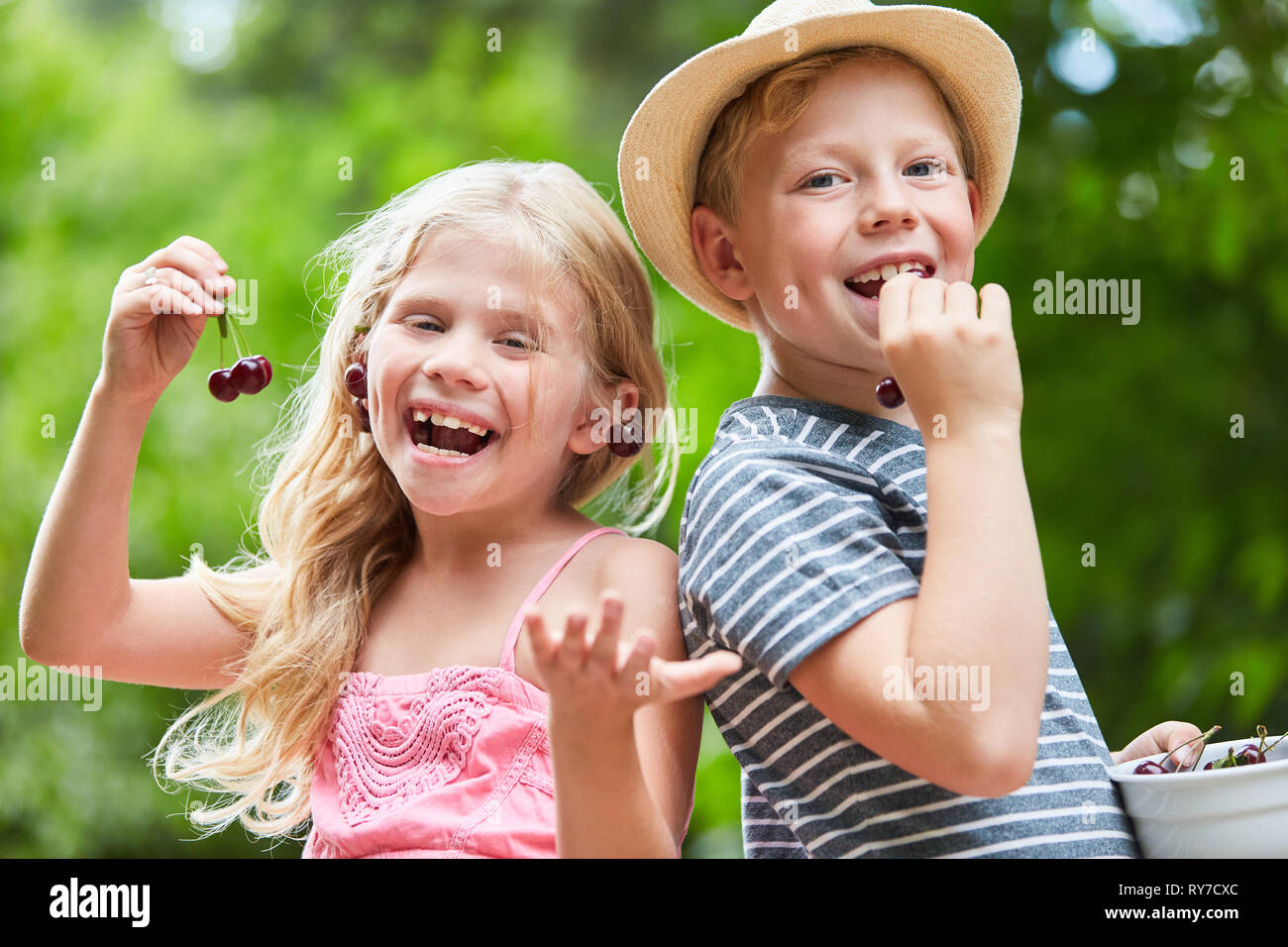 Deux heureux les enfants mangent les cerises ensemble dans le jardin en été Banque D'Images