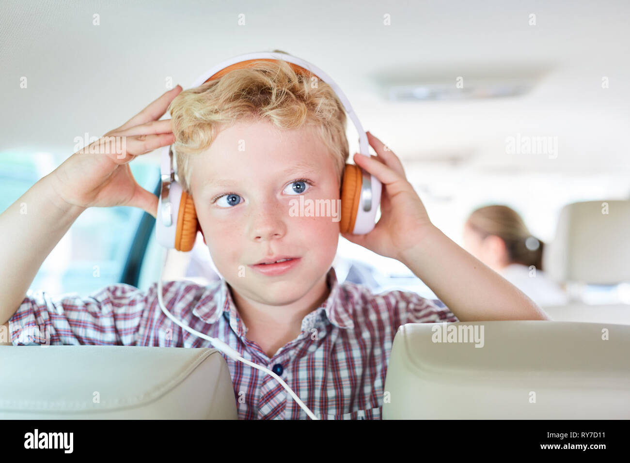 Garçon avec un casque dans la voiture est à l'écoute de la musique en continu sur le voyage en ligne Banque D'Images