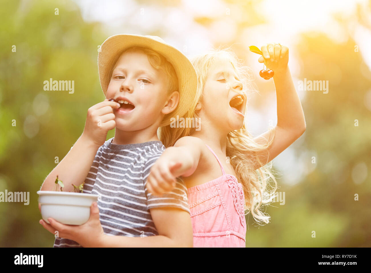 Deux enfants manger des cerises dans le jardin d'été Banque D'Images