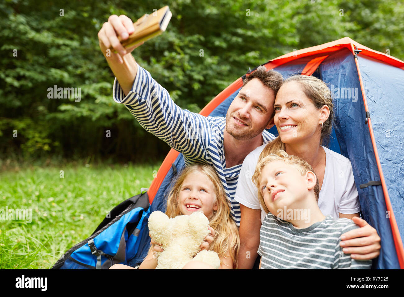 Famille heureuse avec deux enfants est de prendre un camping en été tout en selfies Banque D'Images