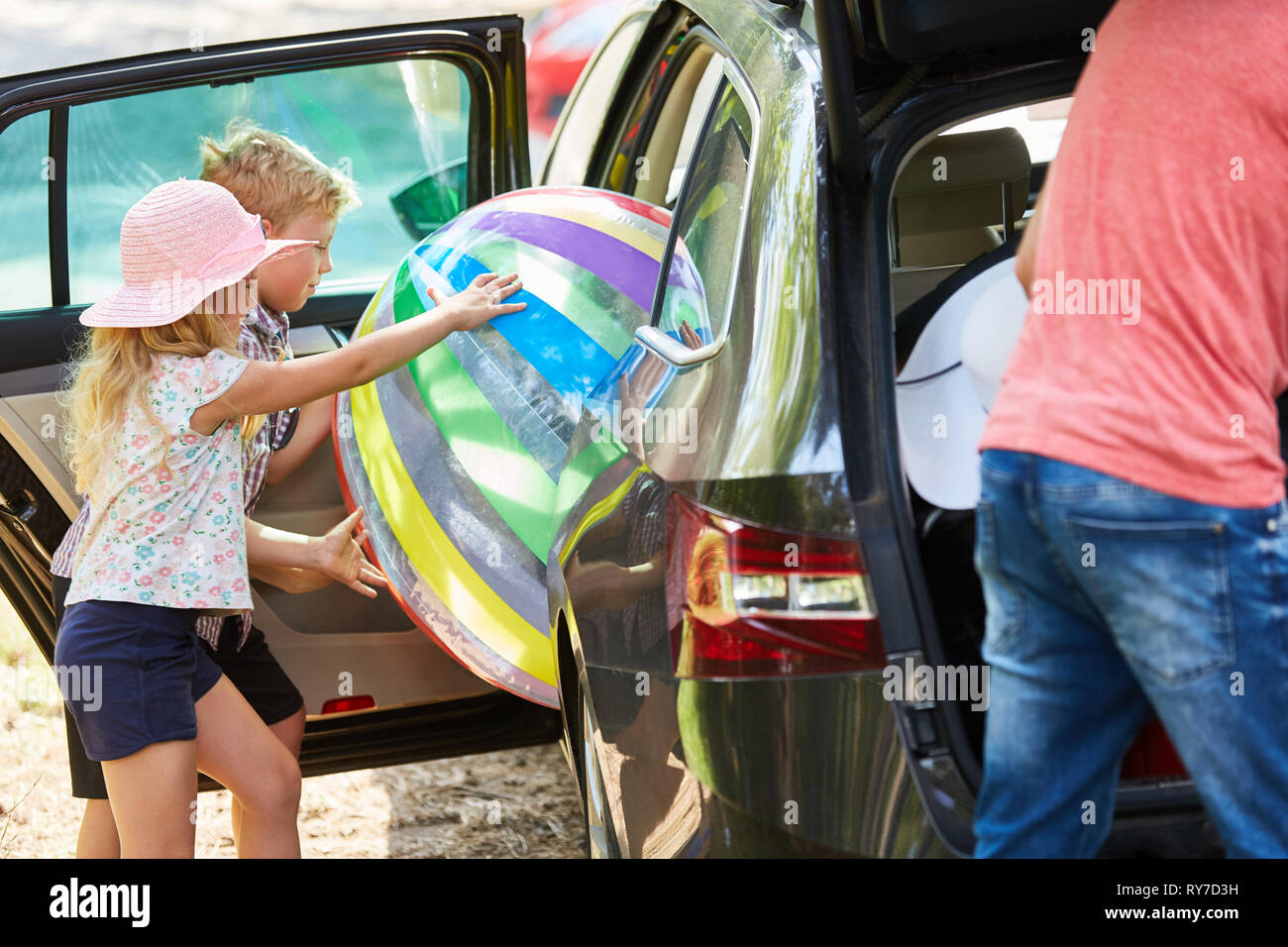 Enfants charger une grosse boule dans la voiture avant de partir en vacances d'été Banque D'Images