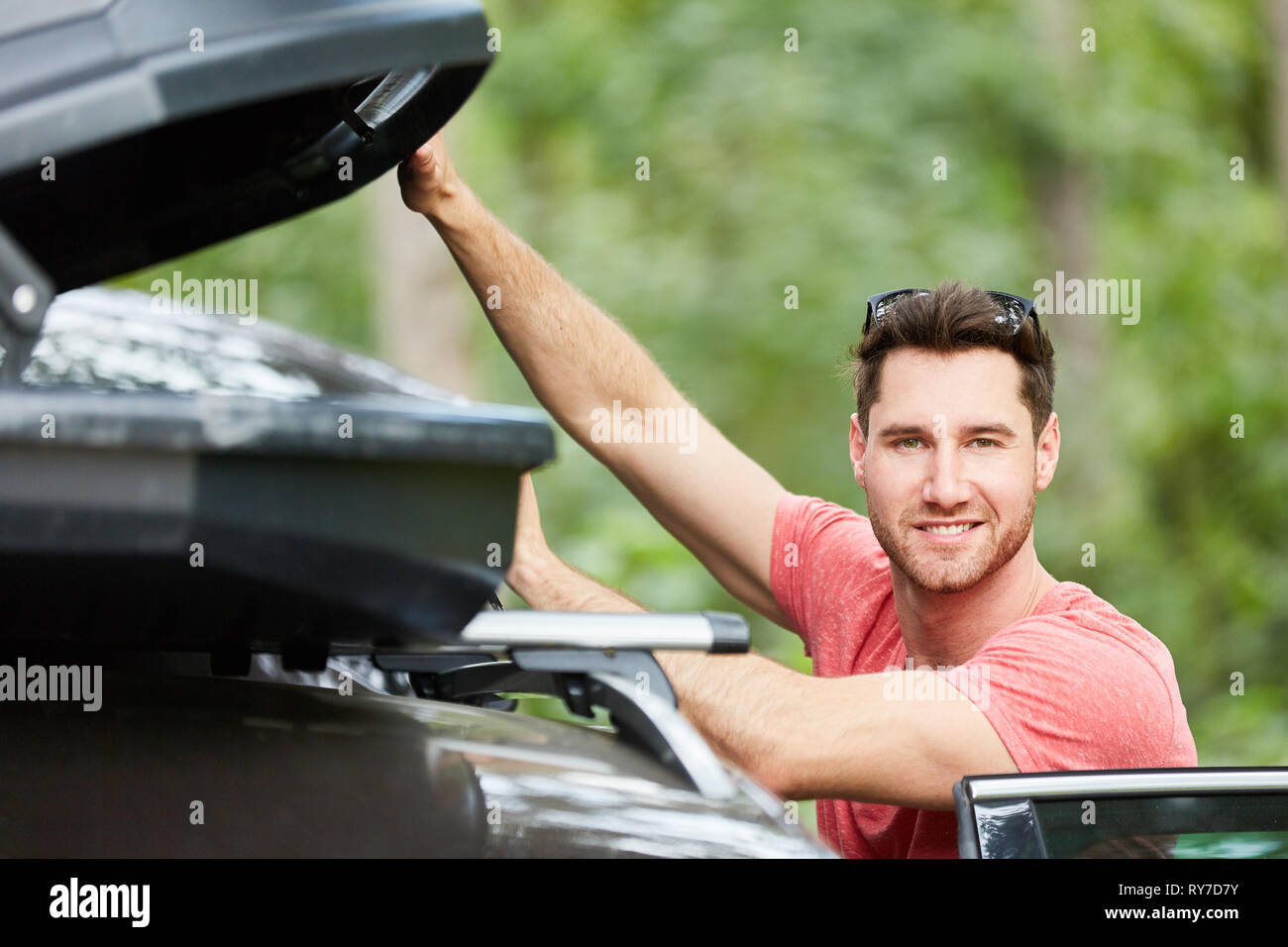 L'homme se compose d'un coffre de toit pour bagages sur le toit de voiture avant les vacances Banque D'Images