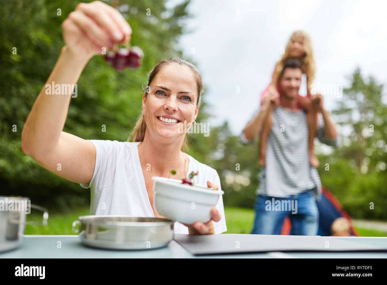Femme avec des cerises fraîches sur le camping. Les vacances d'été avec la famille Banque D'Images