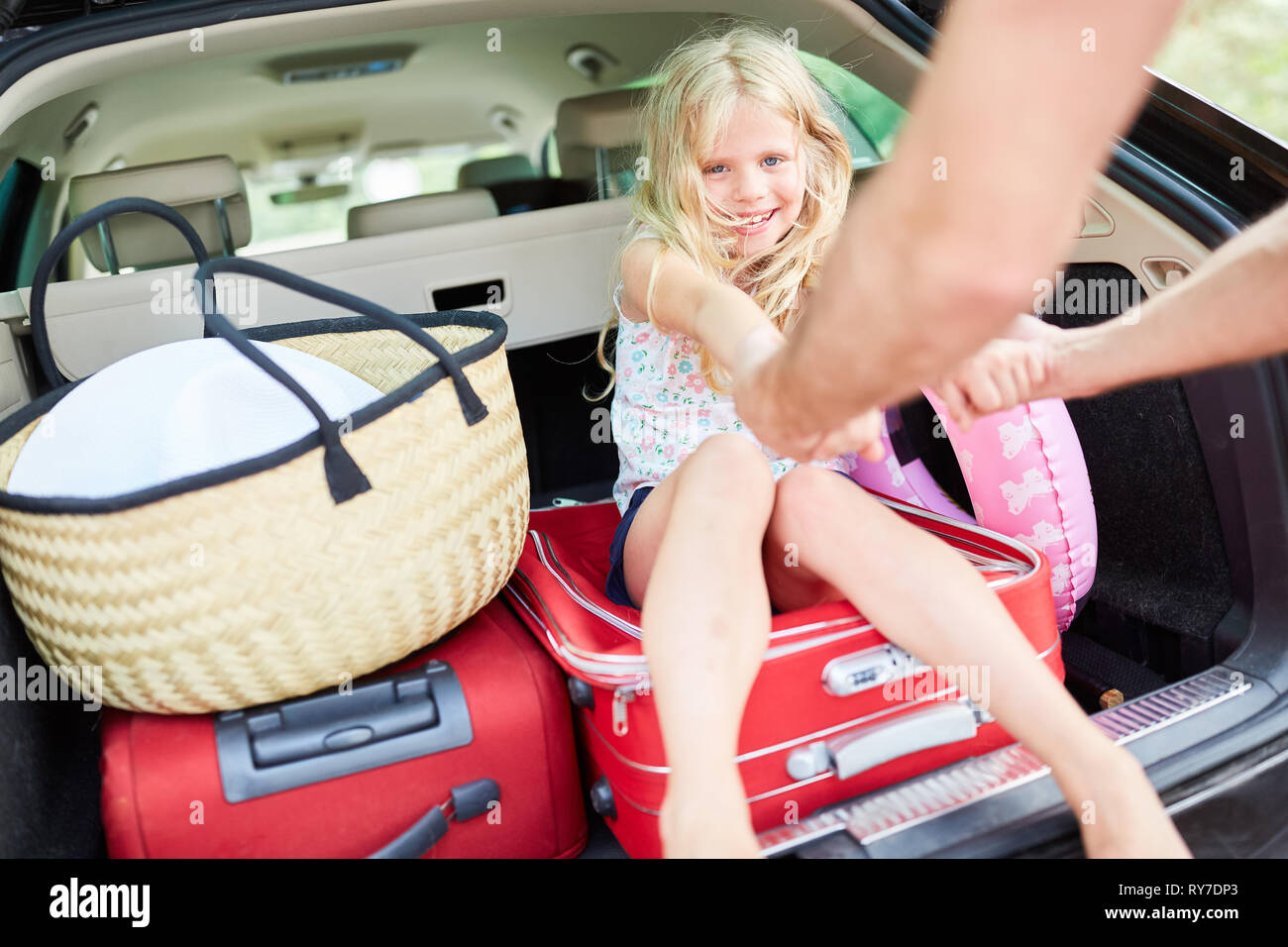 Cheerful girl est assis sur l'assurance dans le coffre de la voiture avant de partir en vacances Banque D'Images
