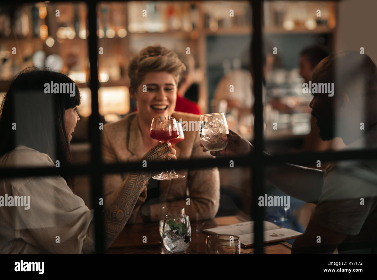 Smiling friends toasting avec boissons dans un bar de nuit Banque D'Images