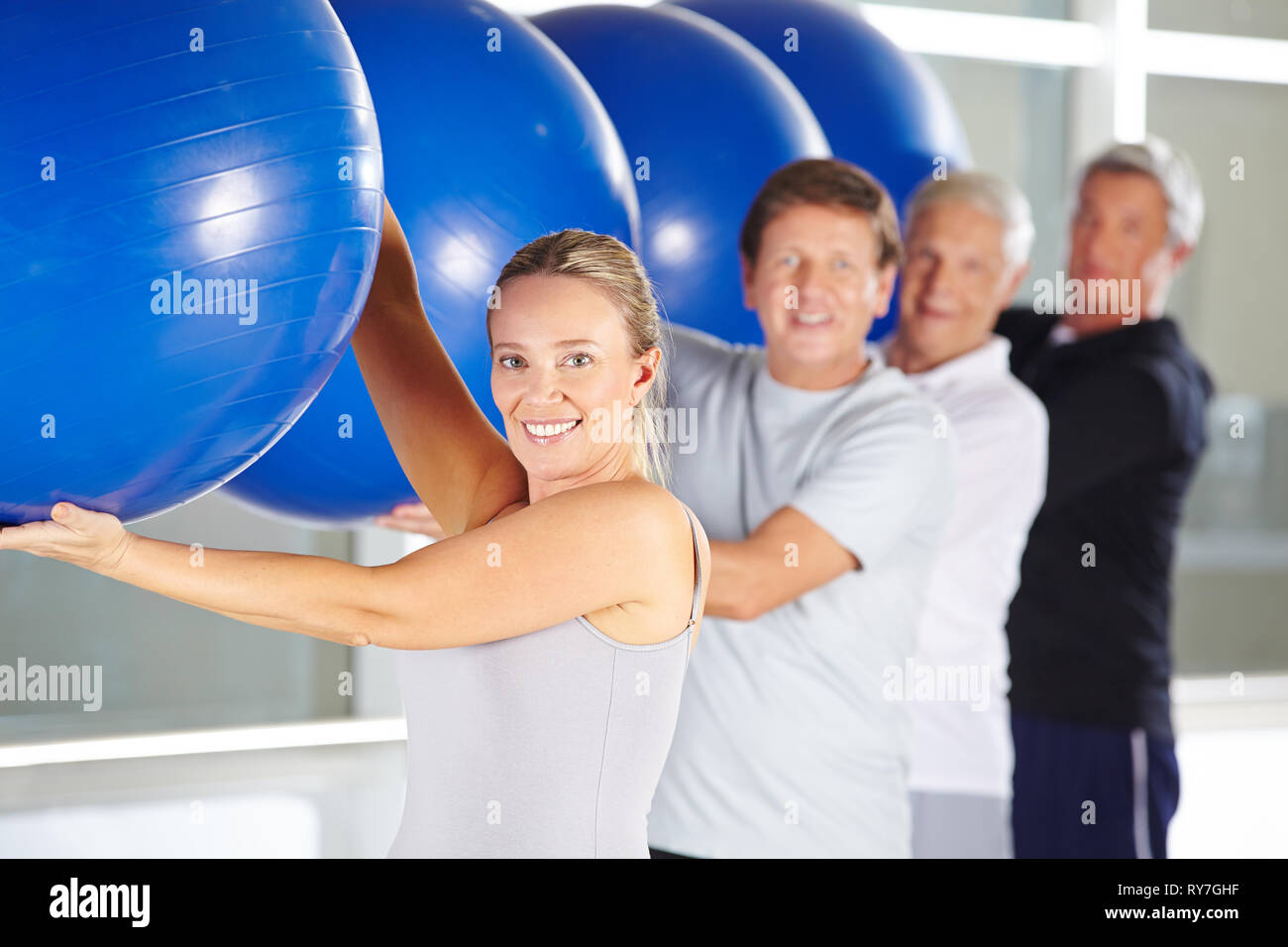 Groupe de personnes âgées en souriant tout en exerçant en centres de réadaptation avec balles de gymnastique Banque D'Images
