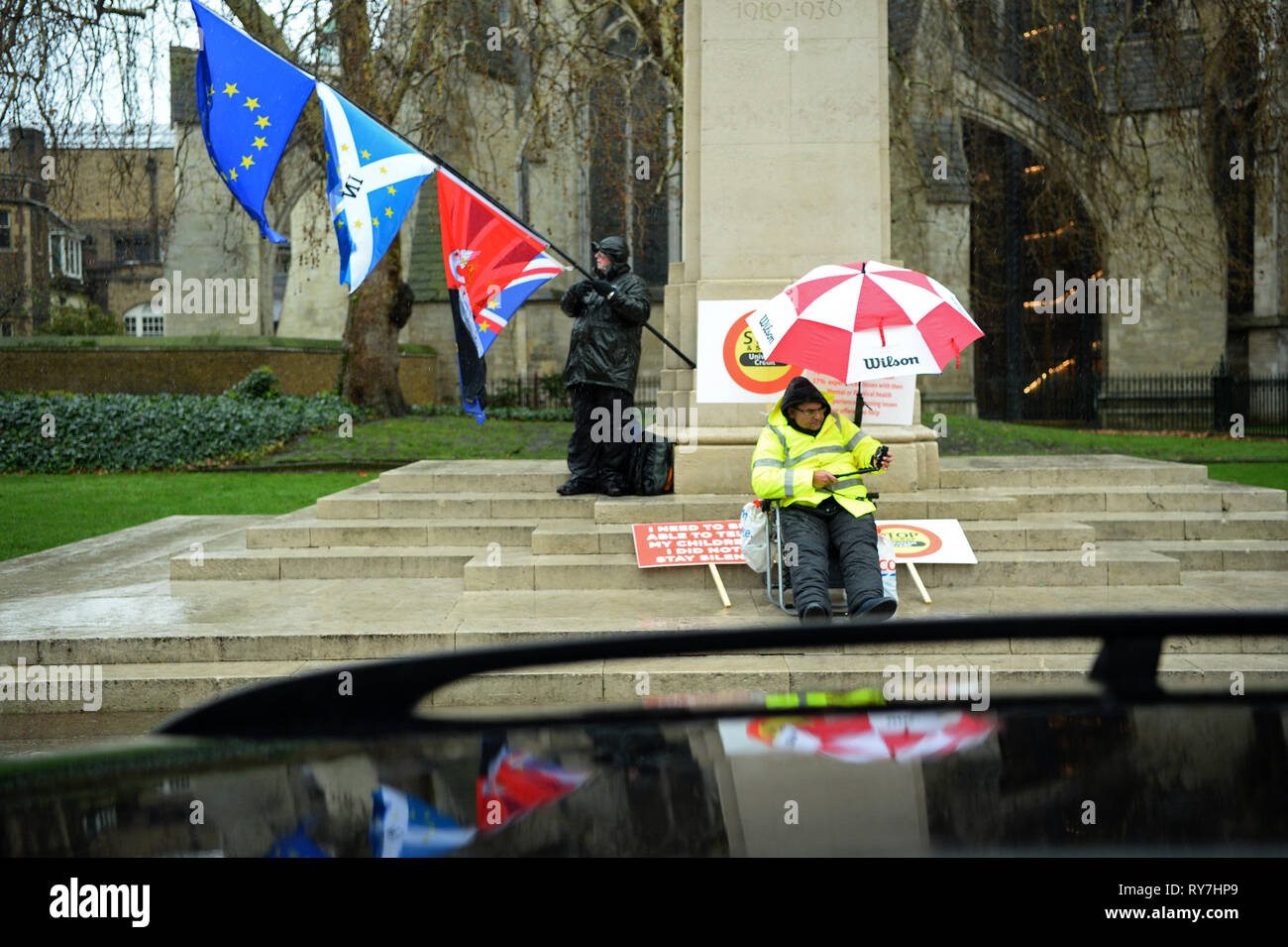 Un Brexit partisan et un homme à manifester leur désaccord sur le crédit universel sous la pluie à Westminster, Londres. Banque D'Images