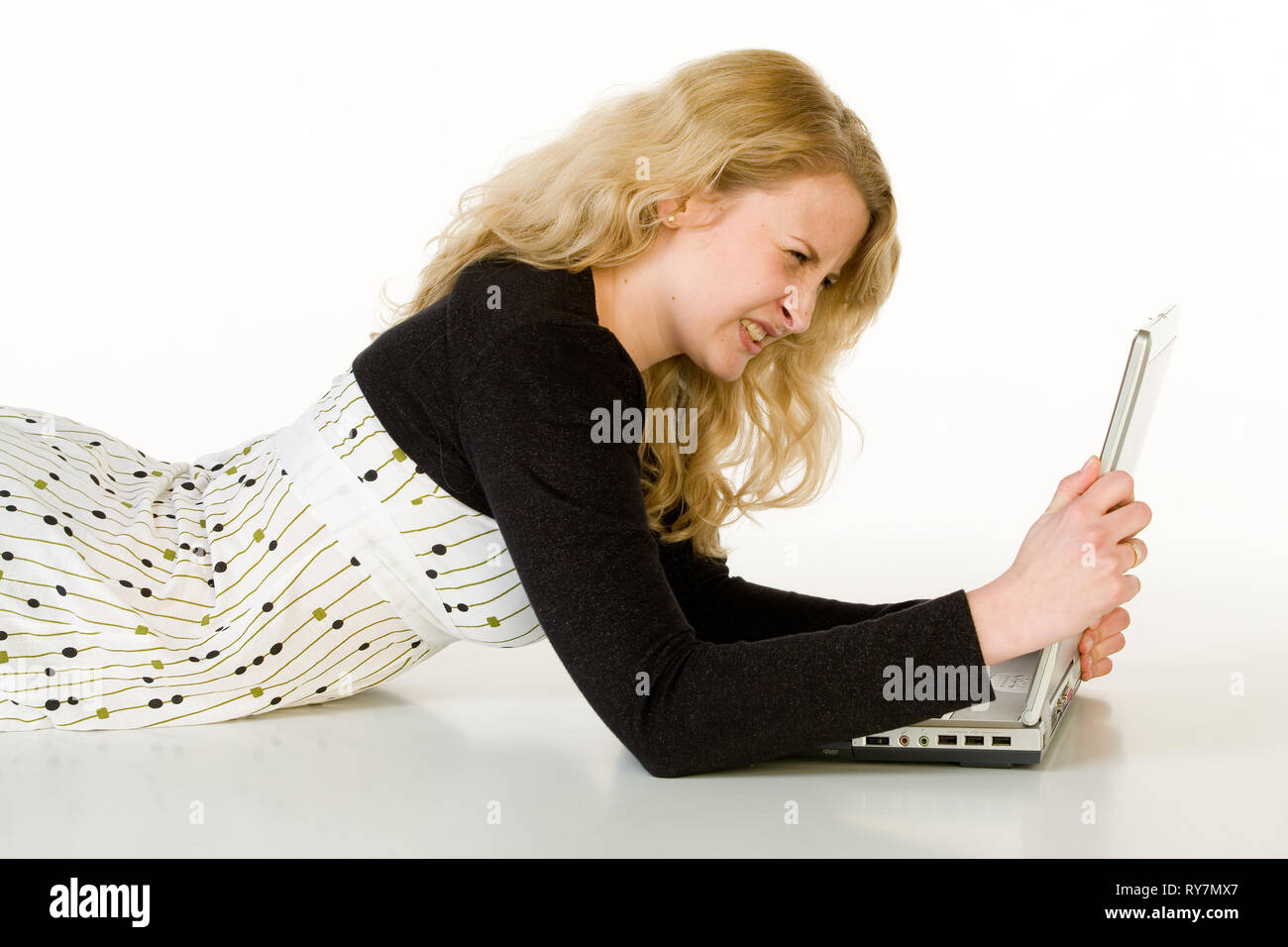 Une jeune femme se trouve en face de son ordinateur portable. Isolé à partir d'un fond blanc. Banque D'Images