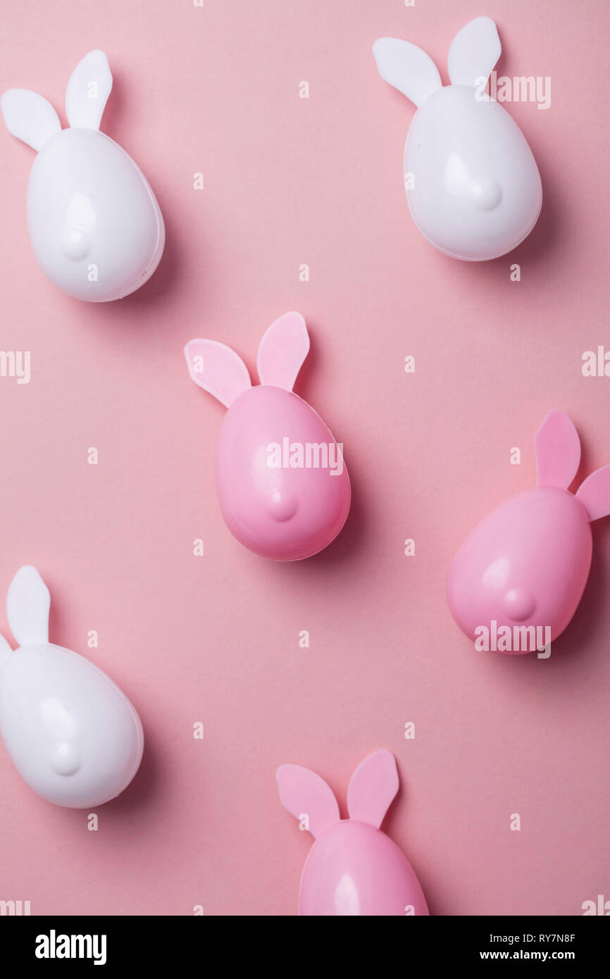 Les oeufs de Pâques avec des oreilles de lapin sur un fond rose pastel Banque D'Images