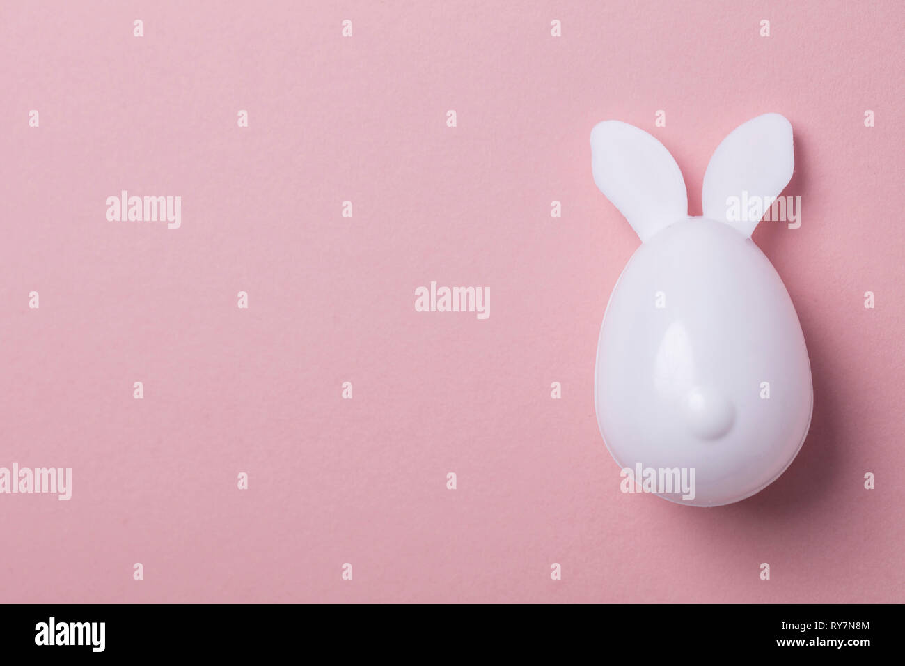 Œuf de Pâques avec des oreilles de lapin sur un fond rose pastel Banque D'Images