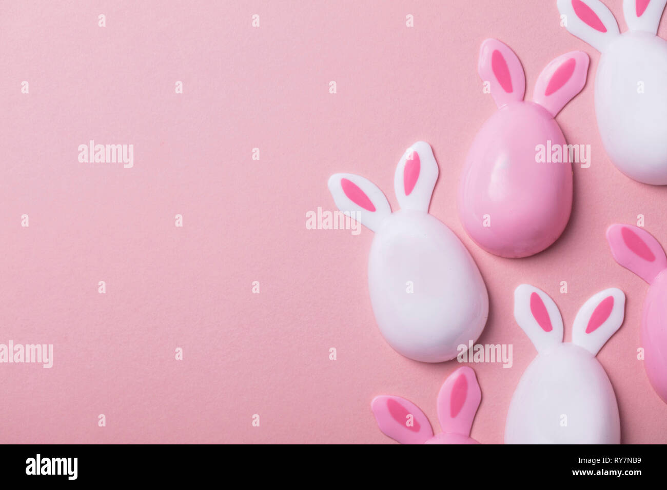 Les oeufs de Pâques avec des oreilles de lapin sur un fond rose pastel Banque D'Images
