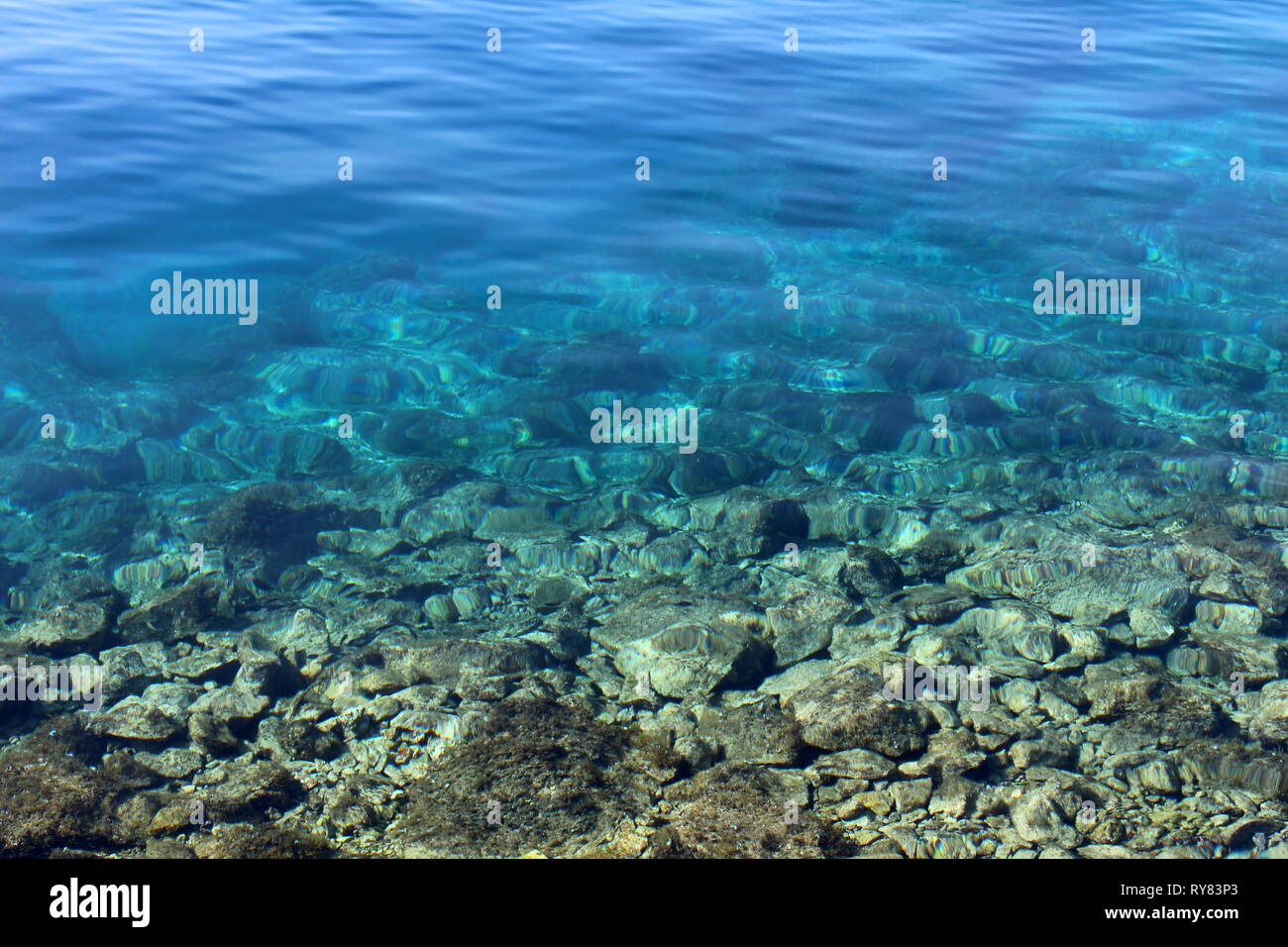 Bleu de la mer calme avec roches clairement visible sur le bas allant de faible à l'extrémité profonde sur le printemps chaud et ensoleillé Banque D'Images