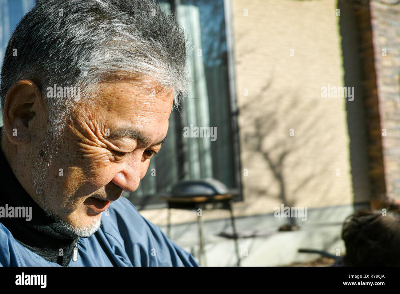 Un vieux Asian man smiling while looking down Banque D'Images