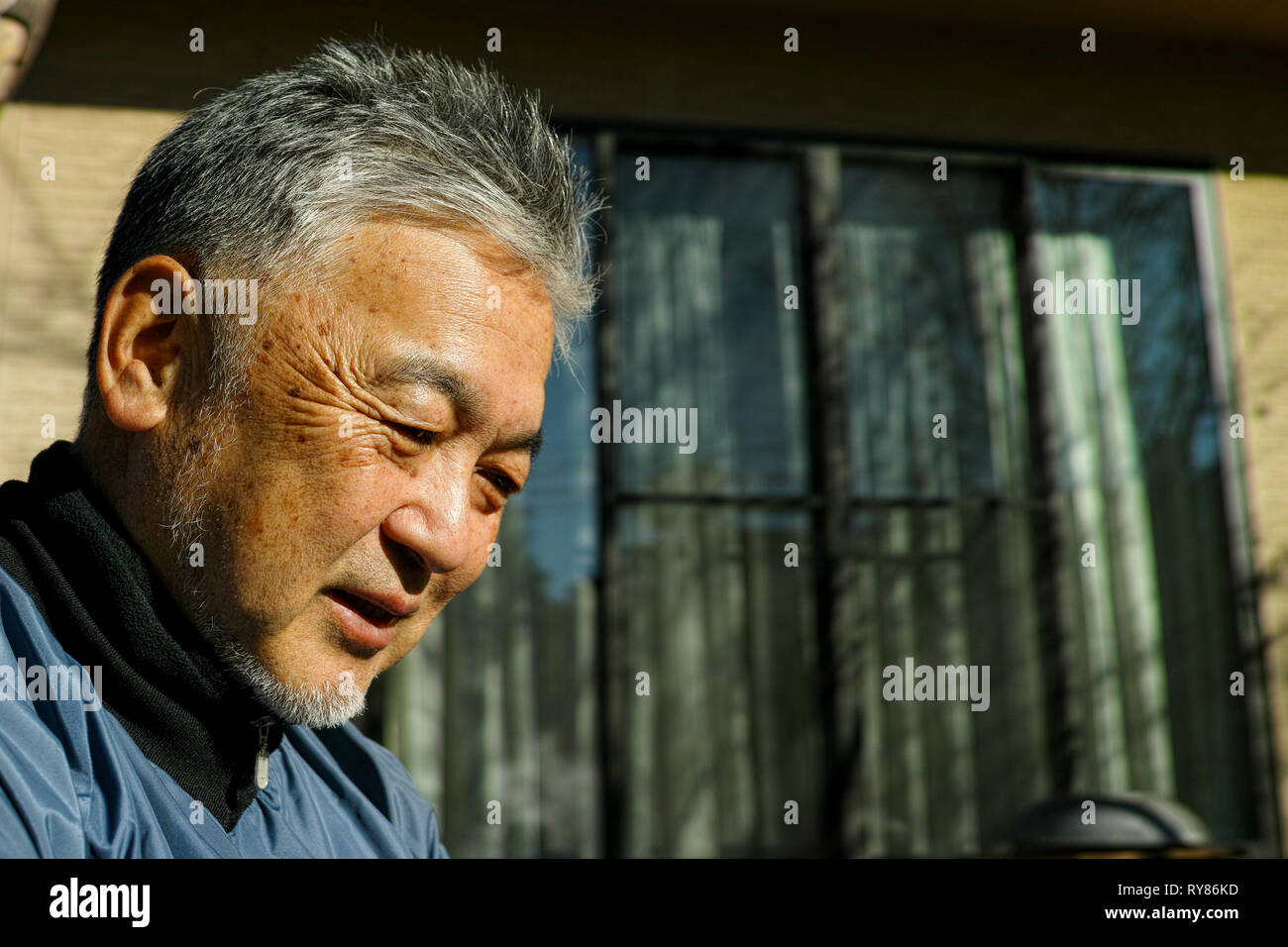 Un vieux Asian man smiling while looking down Banque D'Images