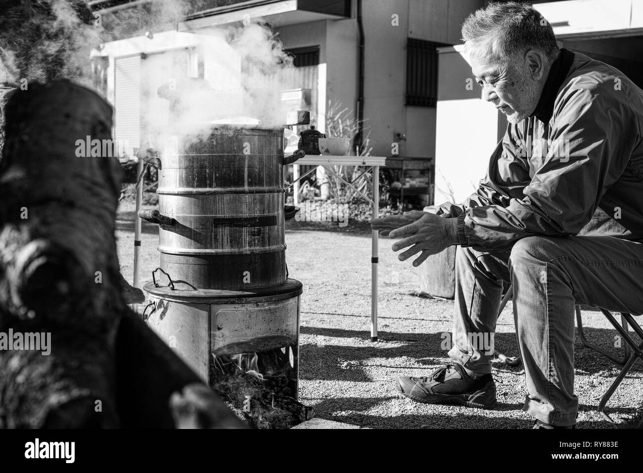 Un ancien homme d'Asie de se réchauffer par le feu de camp Banque D'Images