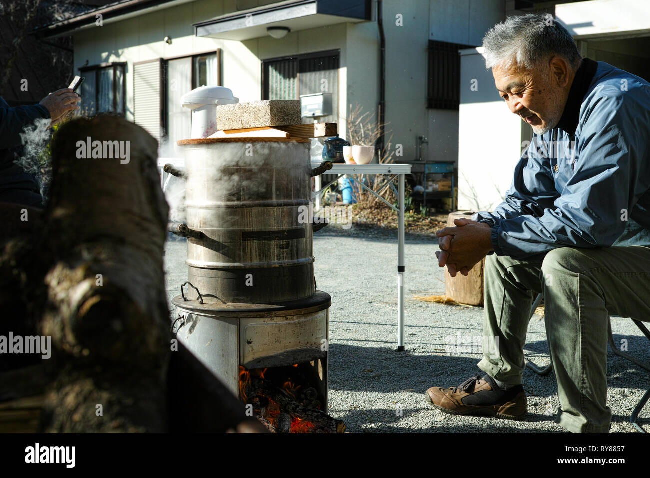 Un ancien homme d'Asie de se réchauffer par le feu de camp, smiling Banque D'Images
