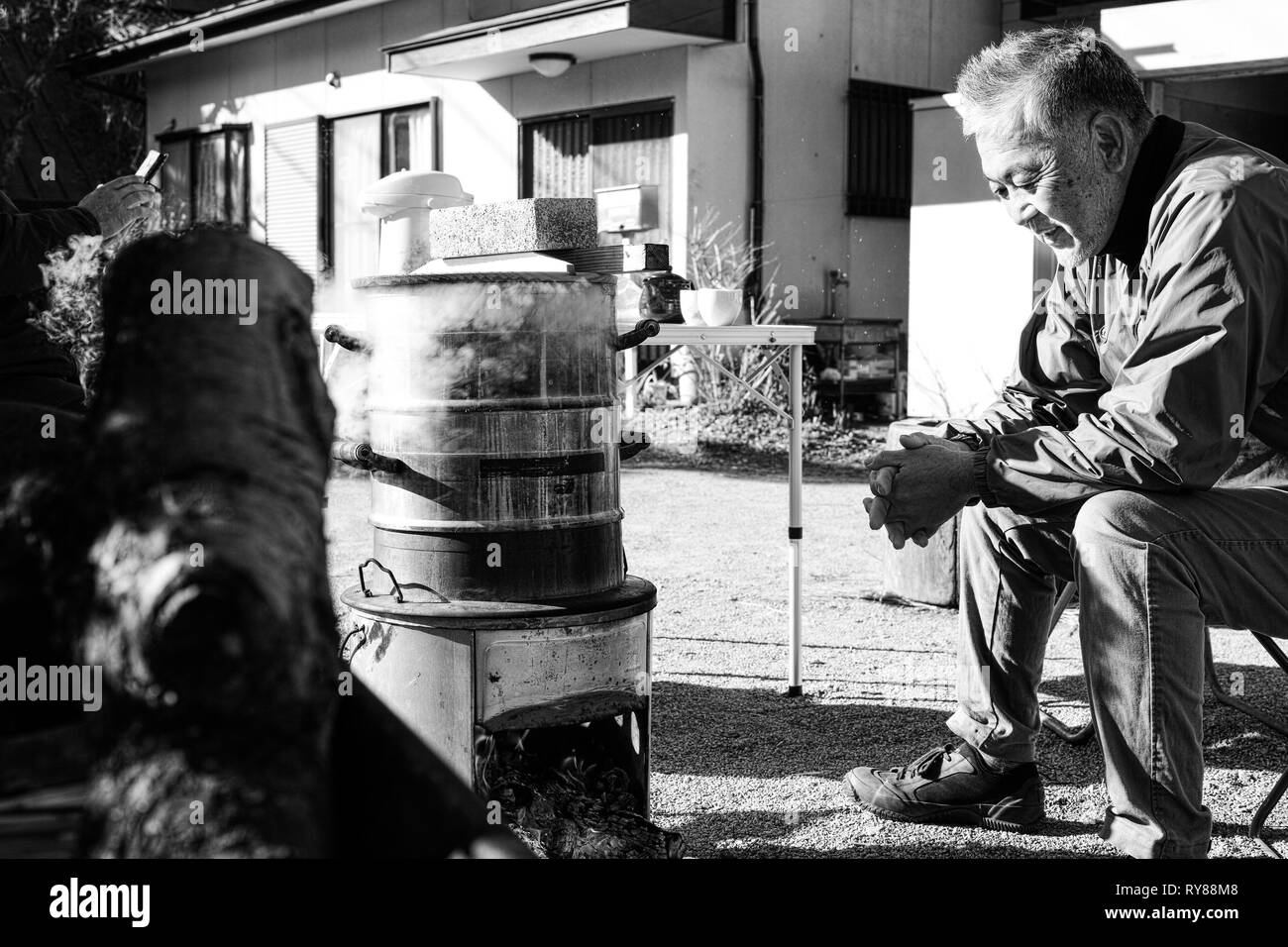 Un ancien homme d'Asie de se réchauffer par le feu de camp Banque D'Images