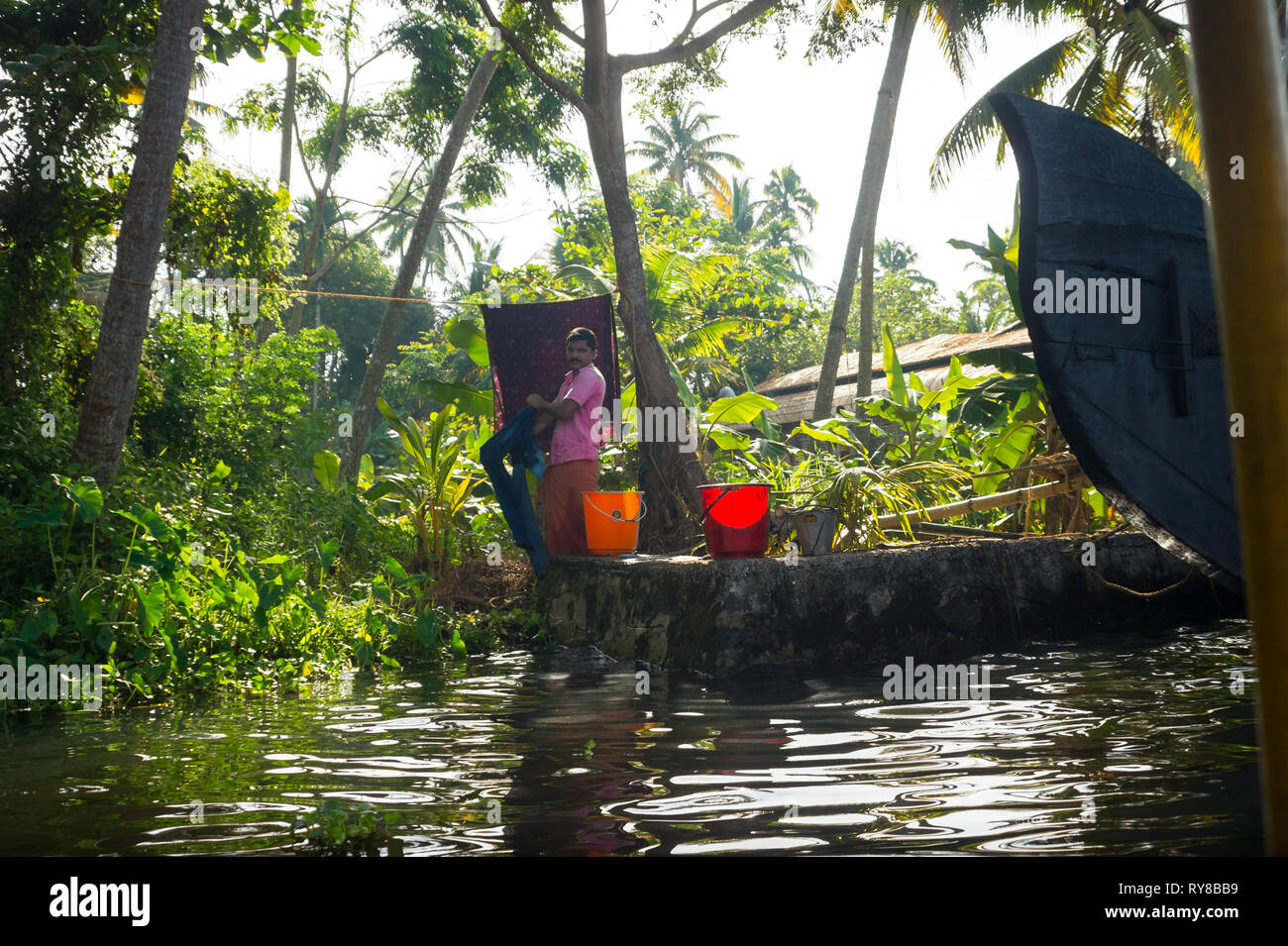 Village indien man main lave des vêtements le long de la Kerala Backwater - Alleppey, Inde Banque D'Images