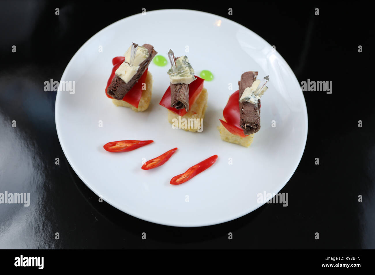 Viandes tranchées, roulé dans un rouleau, des canapés avec du fromage bleu et rouge, sur une brochette, close-up, pour le menu Banque D'Images