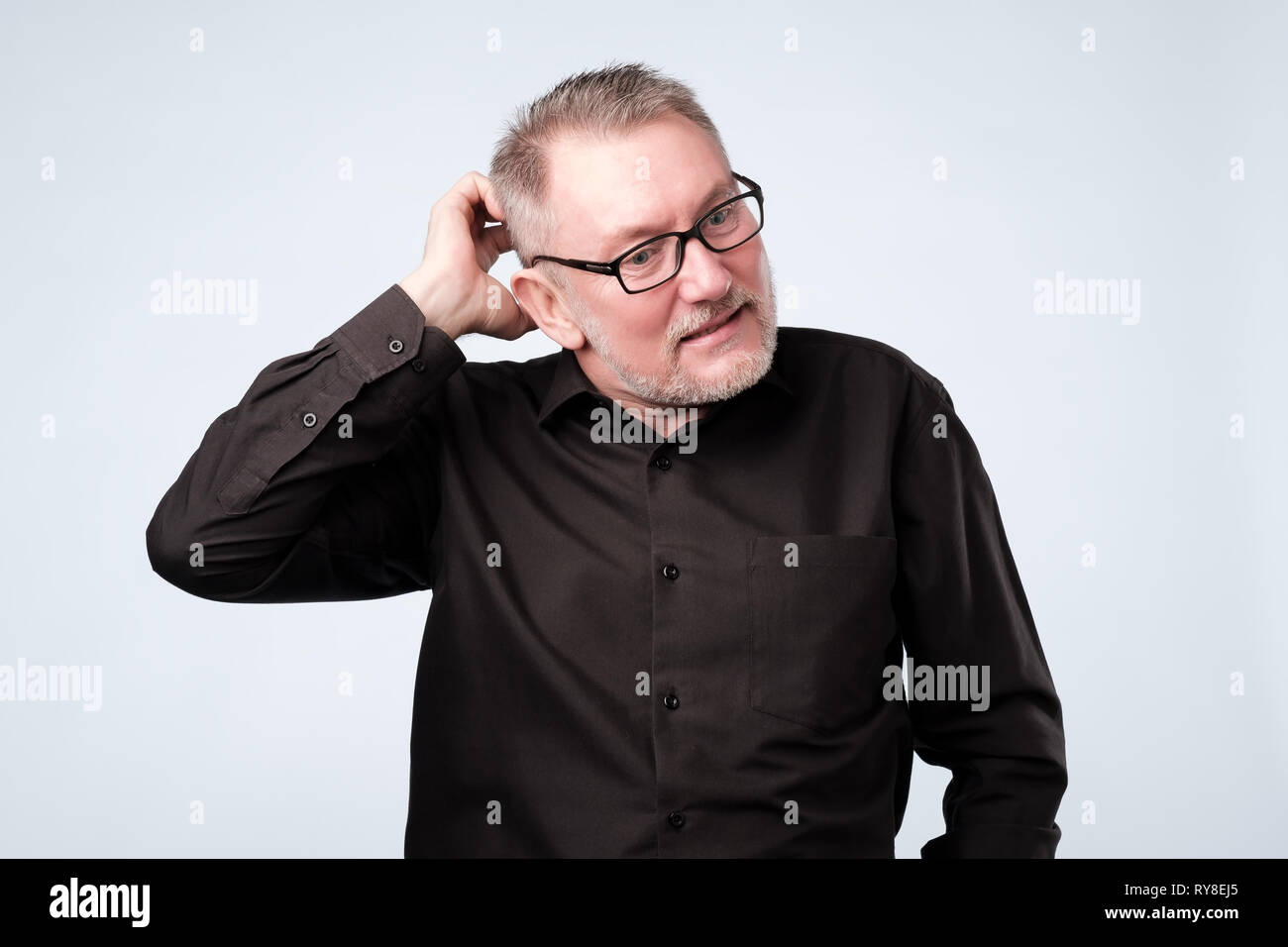 Homme européen en chemise noire et verres de penser à ses problèmes. Banque D'Images
