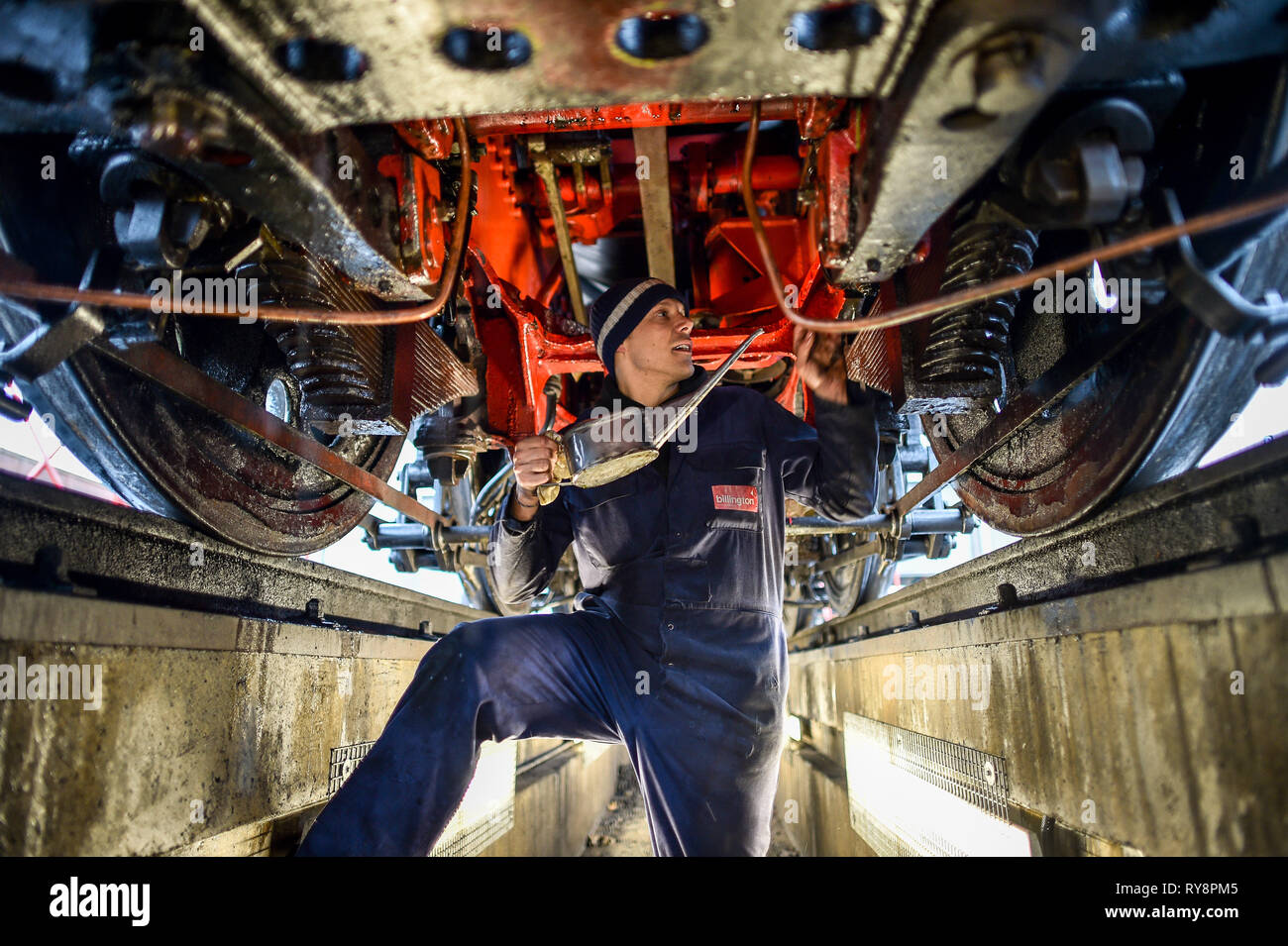 Ben pilote moteur Huile de lubrification en Evason verse des pièces en mouvement de l'axe de SR ? ? ?marine marchande ? ? ? N° du Pacifique 35006 ? ? ?Peninsular & Oriental SN Co ? ? ? À partir de l'intérieur d'une fosse de visite comme locomotives sont préparés pour le service dans le Gloucestershire Warwickshire Steam Railway station à Toddington, où un patrimoine spécial service de train express à vapeur prend des amateurs de course de Cheltenham. Banque D'Images