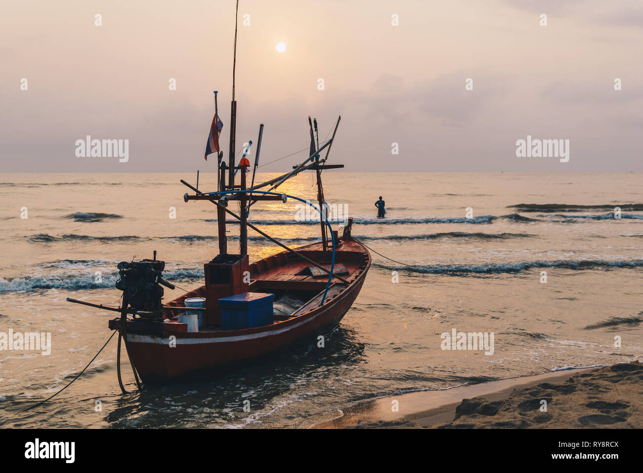 Longue queue traditionnel bateau de pêche au lever du soleil avec pêcheur sur la côte de Hua Hin, Thaïlande. Banque D'Images