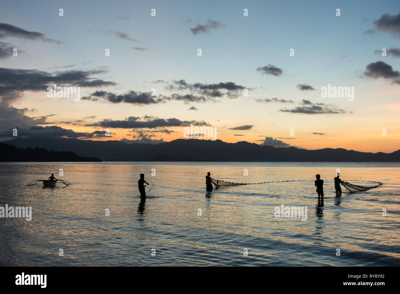 Les pêcheurs tirant un grand filet de la mer, coucher de silhouettes en Port Barton, Palawan - Philippines Banque D'Images