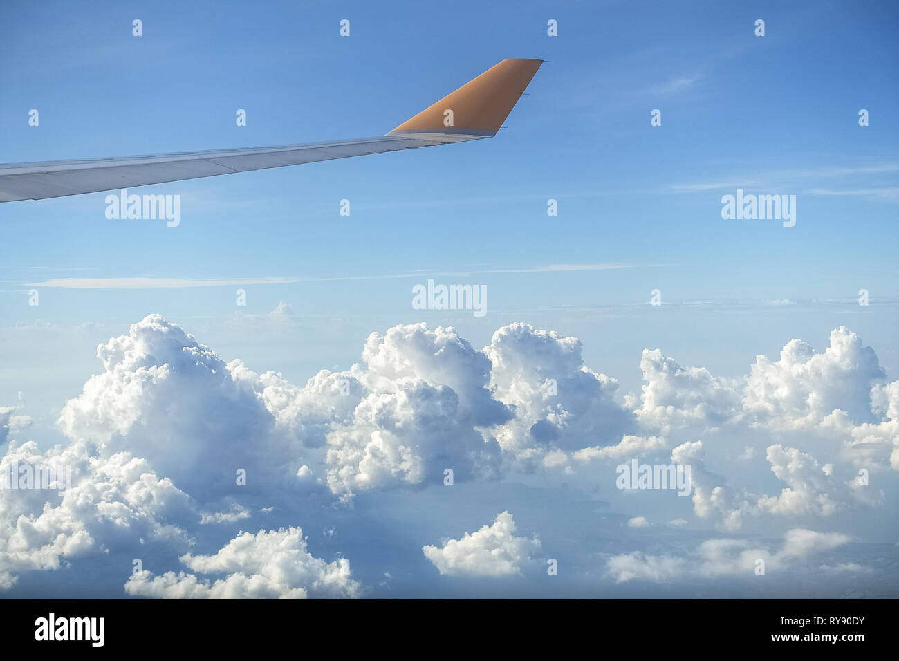 Au-dessus de nuages gonflés parfait, avec l'aile d'avion Jaune sur Bleu Clair Jour Banque D'Images