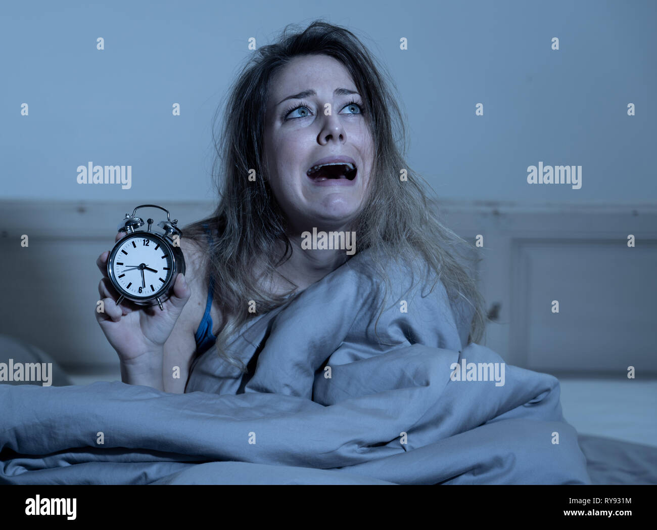 Sleepless et désespérés belle femme caucasienne de dormir la nuit, pas pu dormir, montrant réveil, se sentant frustrés et inquiets souffrant d'insom Banque D'Images